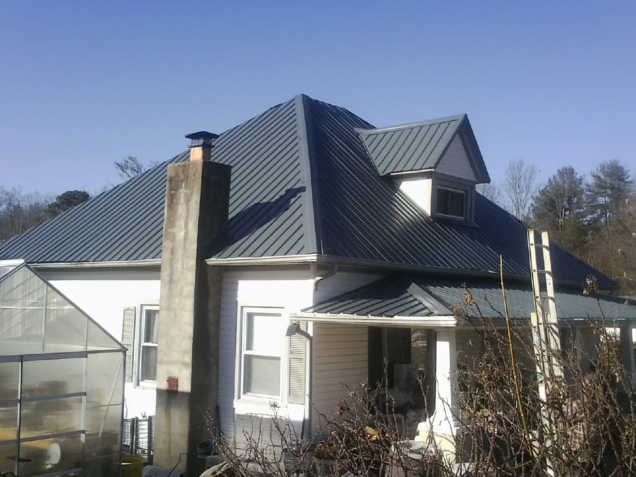 Dark blue standing seam metal roof on a white farmhouse with dormer — Slate & Tile Roof Repair by Roofing Brothers in Shrub Oak