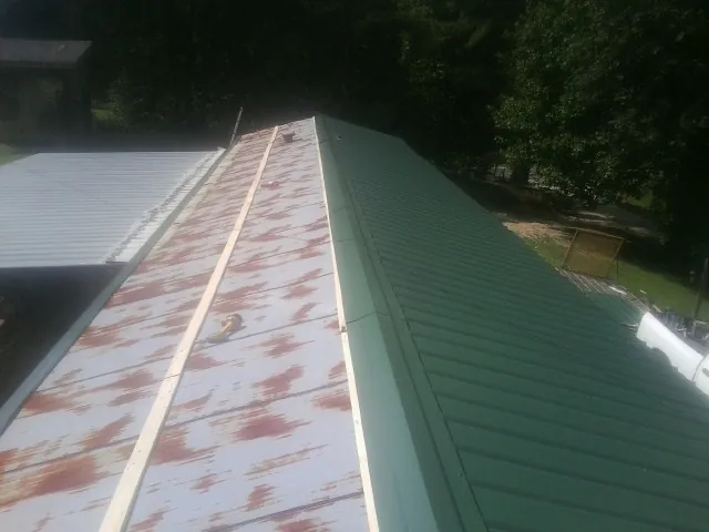 Old rusted panels beside newly installed green metal roofing — Wind Damage Roof Repair by Roofing Brothers in Shrub Oak
