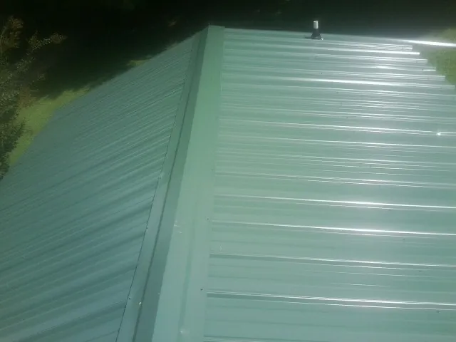 New green metal panels meeting at the ridge of a roof — Flat Roof Repair work by our crew in Shrub Oak