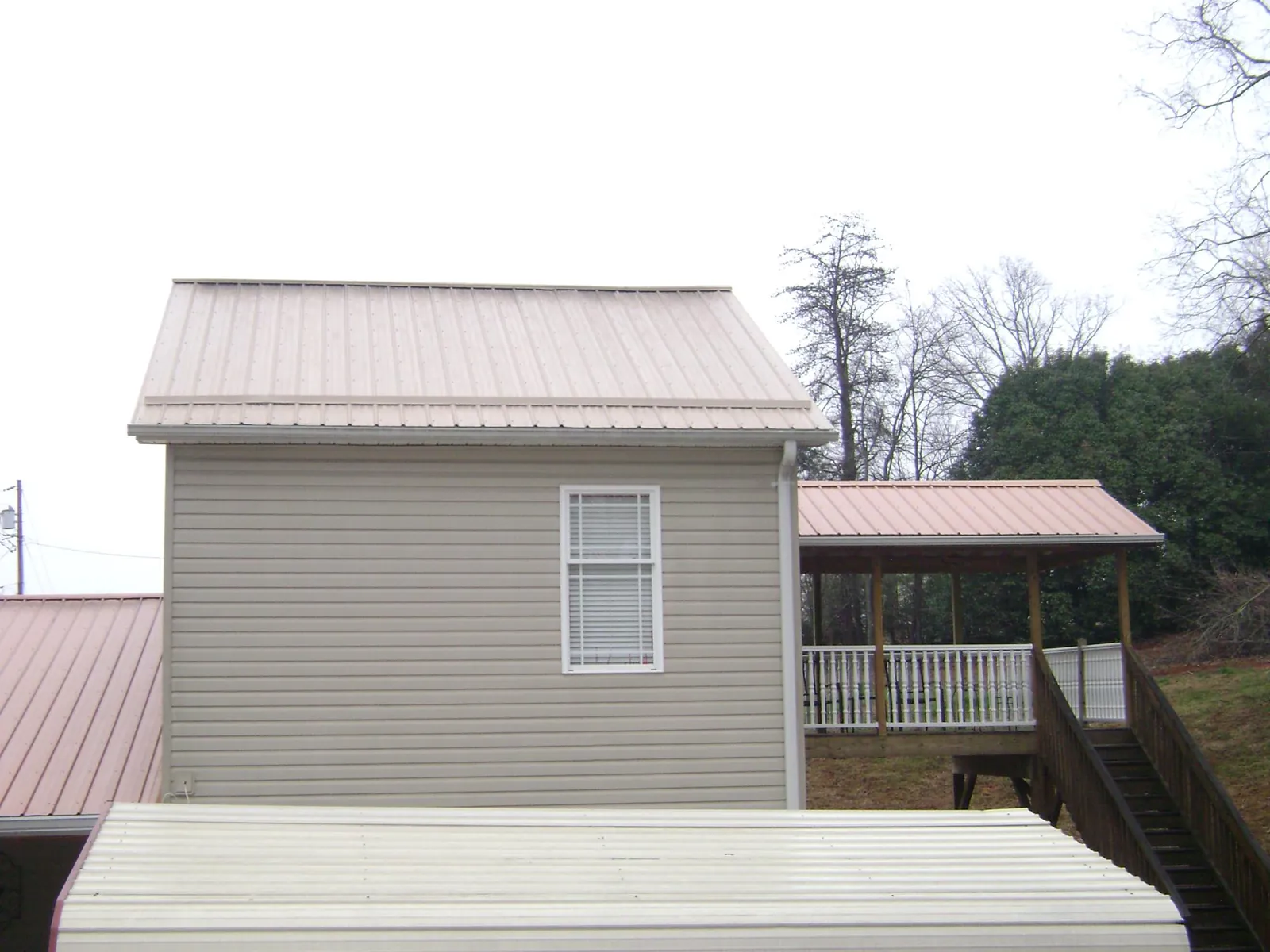 Tan metal roofs on a two story addition and attached porch, from a Roof Replacement job in Shrub Oak