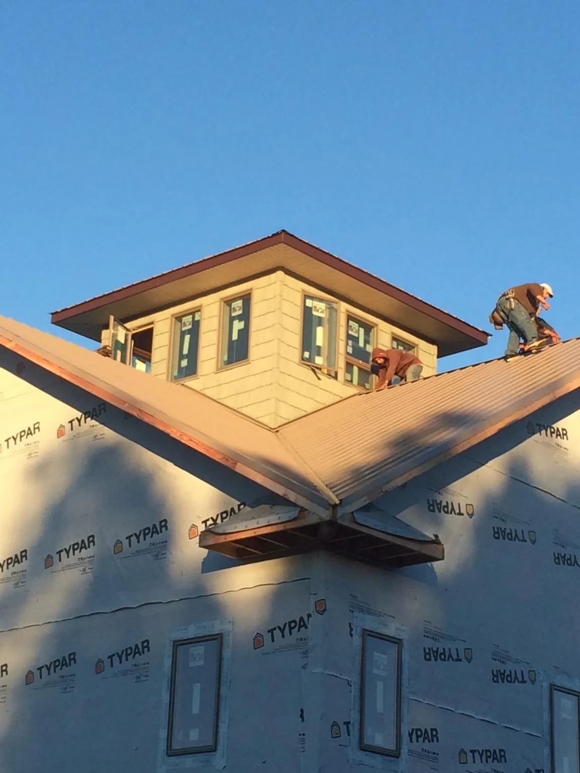 Roofers working around a rooftop cupola on a new metal roof at sunset — Roof Waterproofing in Shrub Oak by Roofing Brothers